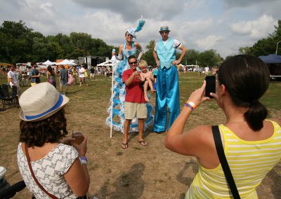 male and female stilt walkers taking photo with family