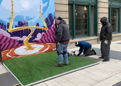 Workers installing football-themed mural and turf