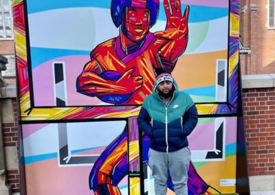 Artist Israel Solomon in front of mural