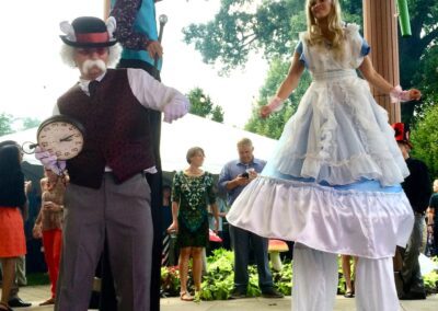Mad Hatter and Alice dancing on stilts with White Rabbit