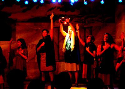 Lysistrata leads women in sacred ceremony under red stage lights