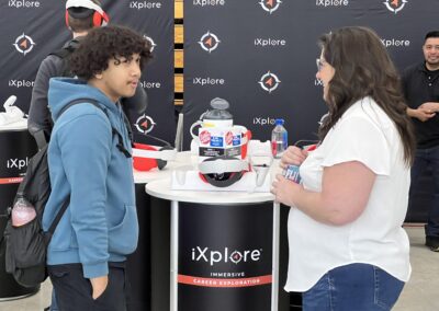 Attendees discussing VR headset at iXplore booth