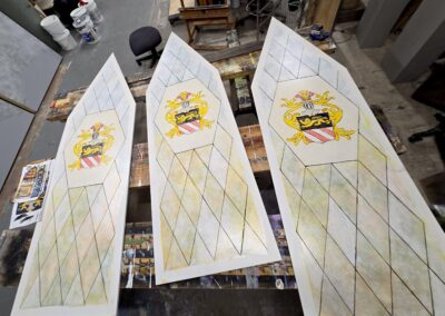 Three painted heraldic wooden panels on table