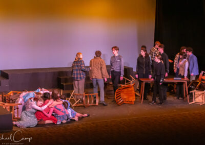 Actors on stage with overturned chairs